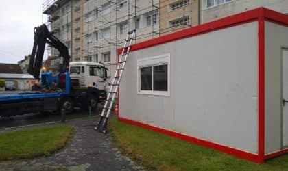 Bungalow gris et rouge installé sur un chantier